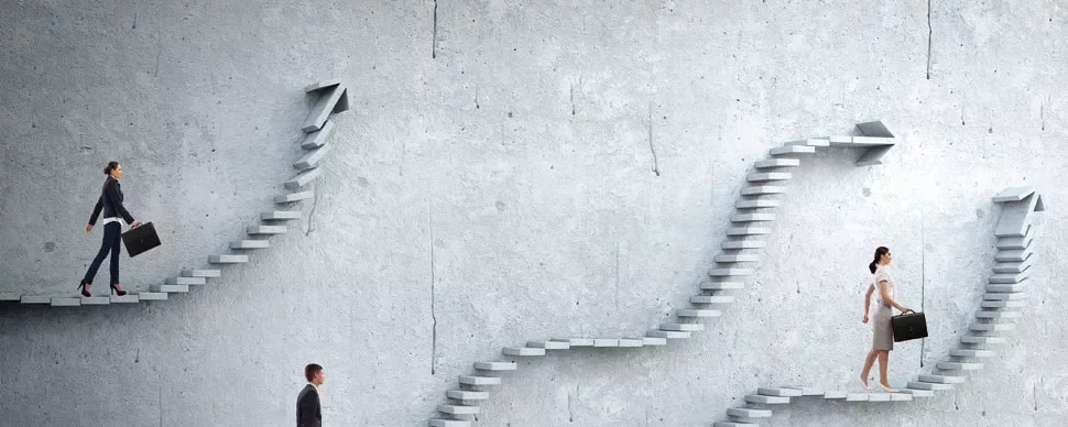 People walking on different staircases against a concrete wall.