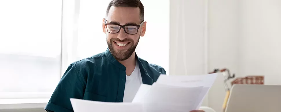 Person smiling while reading documents at a desk.