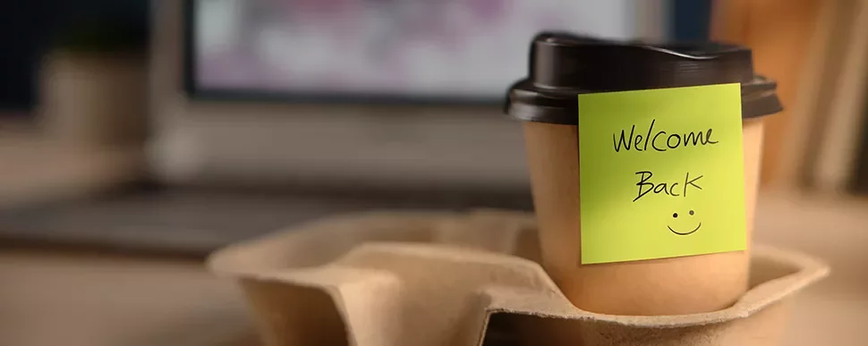 Coffee cup with 'Welcome Back' note and smiley face.