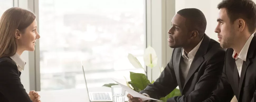 Person in business attire being interviewed by two individuals in an office.