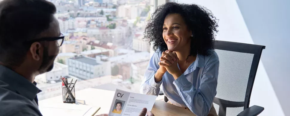 Person smiling during a job interview with a city view in the background.