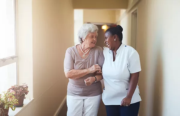 Two people walking and smiling in a hallway.