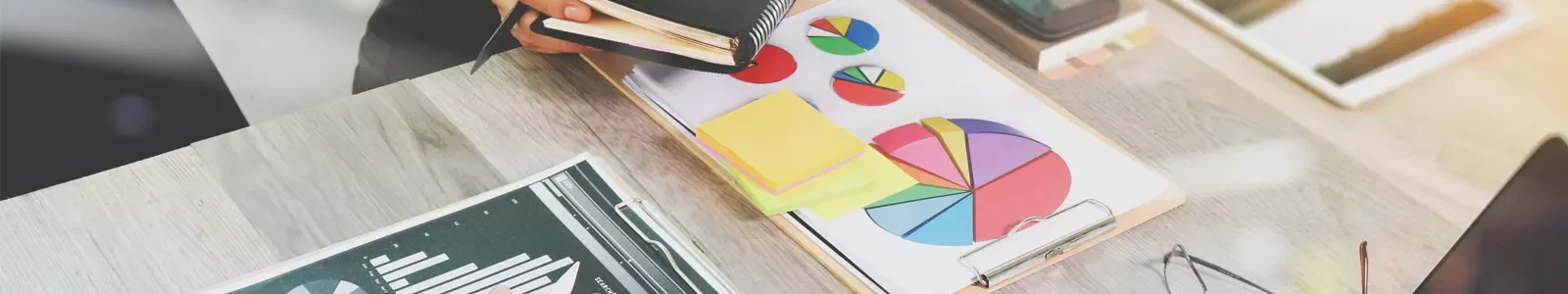 Desk with charts and graphs on paper, open notebook and writing materials.