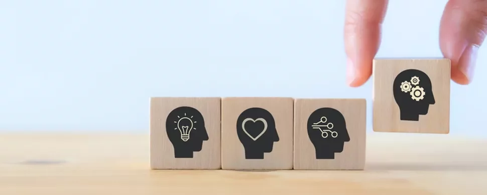 Wooden blocks with head icons depicting ideas, heart, connections, and gears.
