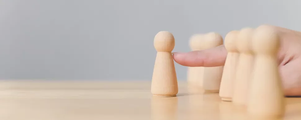 Finger pushing a wooden pawn on a table.