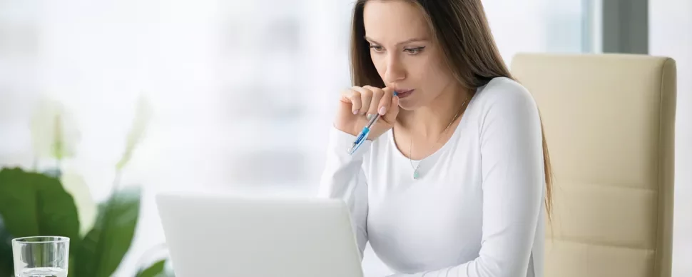 Person in white shirt working on laptop at desk.