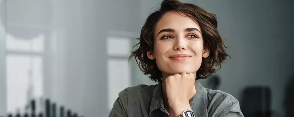 Person smiling with hand under chin, looking thoughtful