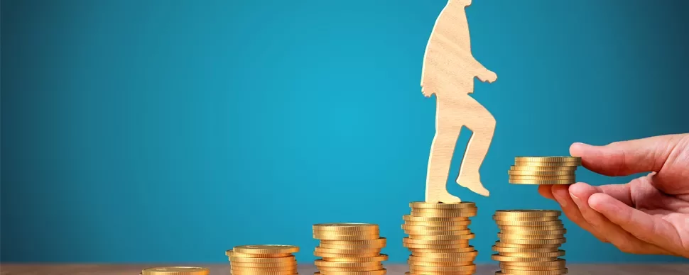 Wooden figure walking up stacks of coins against a blue background.