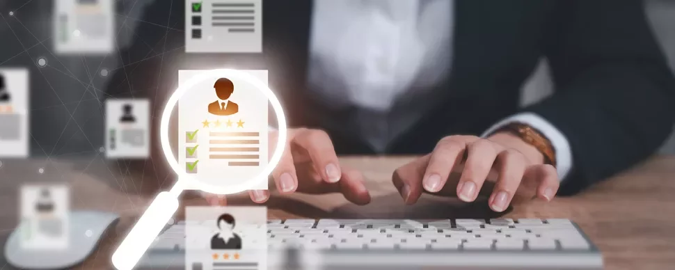 Person typing on keyboard with digital resume and magnifying glass overlay.