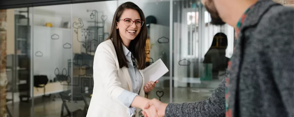 Person smiling and shaking hands in an office setting.