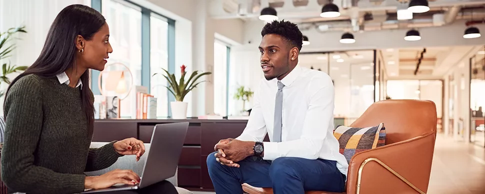 Two people seated in a modern office, engaged in conversation.