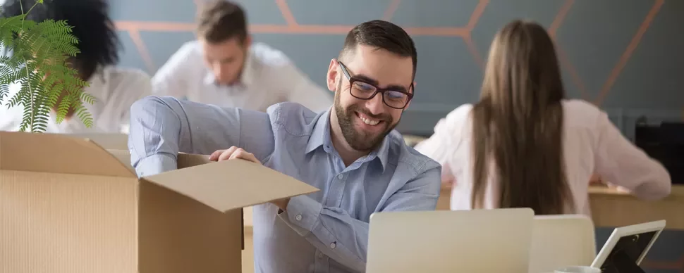 Person smiling while unpacking a box in an office