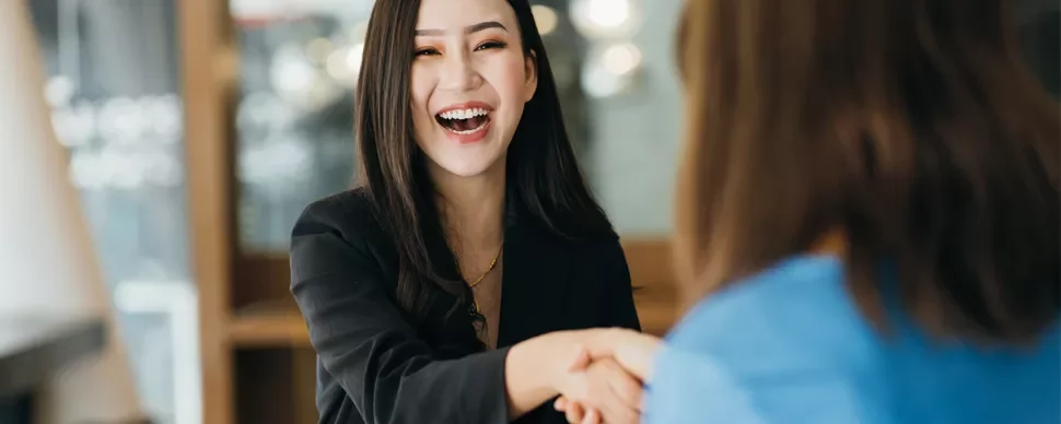 Person smiling while shaking hands in an office setting.