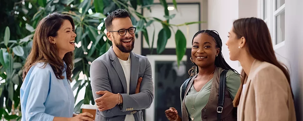 Group of people laughing and talking in an office setting.