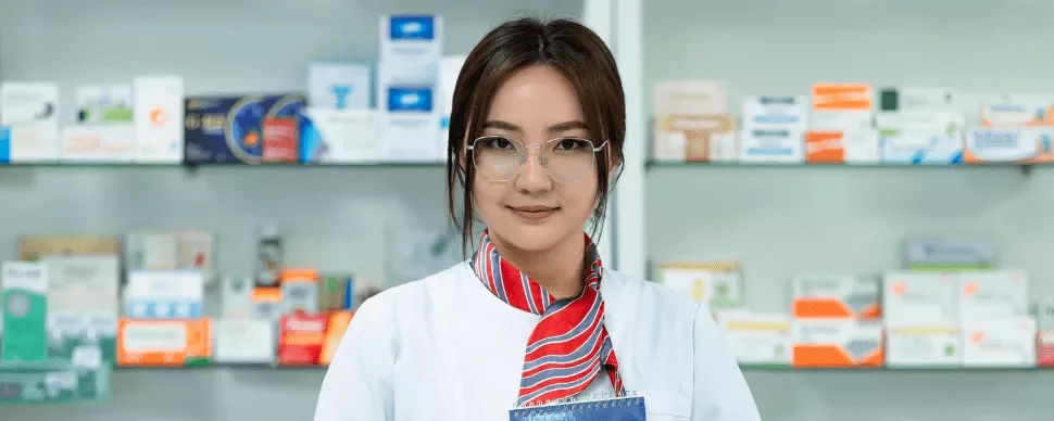 female pharmacist standing in front of shelves of medicine