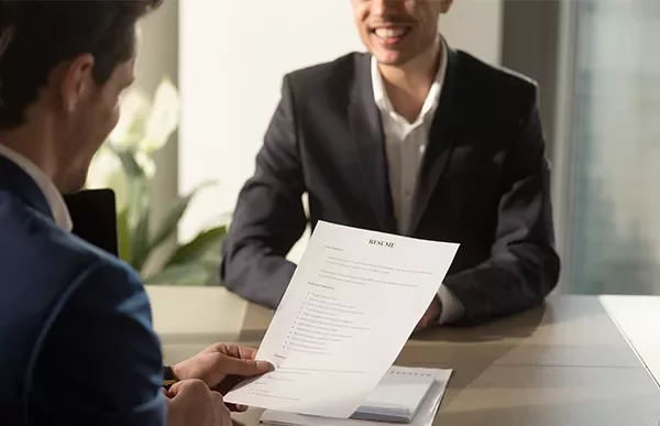 Person holding a resume during a job interview in an office setting.