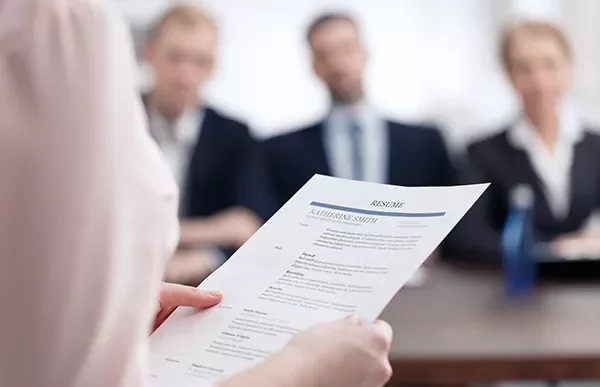 Person holding resume in front of interview panel.