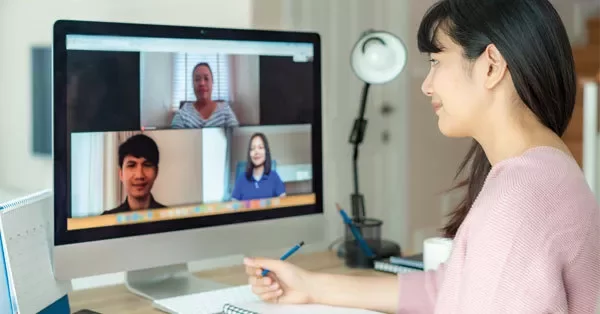 Person participating in a video conference with three others on a computer screen.