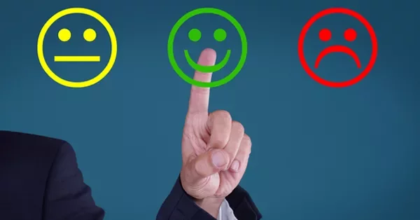 Finger pointing at a green smiling face emoji among neutral and sad faces.