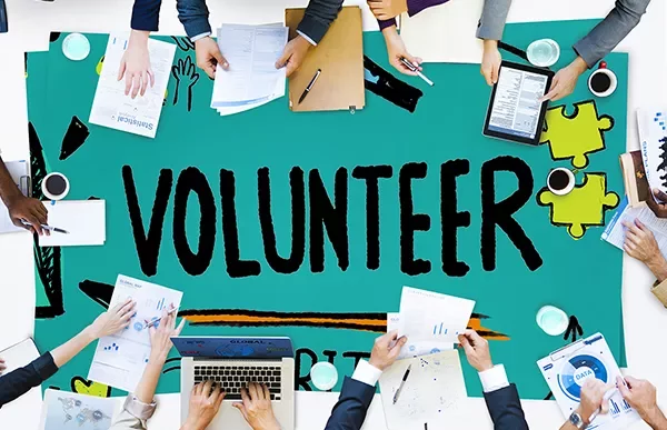 People working together around a table with 'Volunteer' written.
