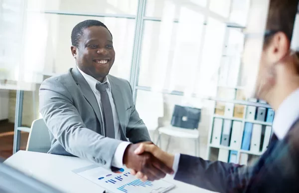 Two individuals shaking hands in an office setting.