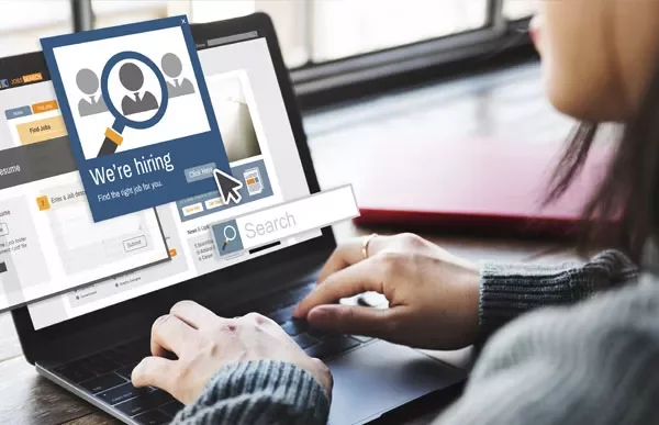 Person using a laptop displaying a 'We're hiring' message on the screen.