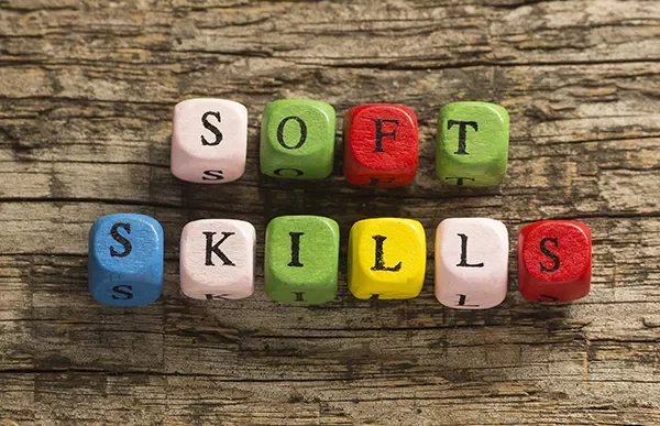 Colorful blocks spelling 'Soft Skills' on wooden background.