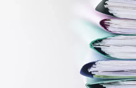 Stack of colorful ring binders filled with documents