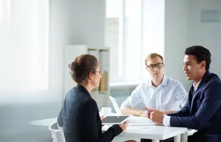 Three people having a meeting in a bright office room.