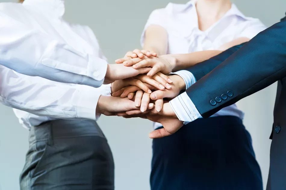 A group of hands stacked together symbolizing teamwork.