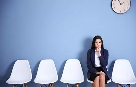 Person sitting on a chair in a room with a blue wall and a clock.