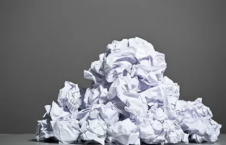 Pile of crumpled white paper against a gray background.