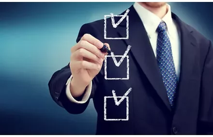 Person in a suit marking completed items on a checklist.