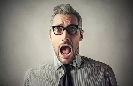 Person wearing glasses and a striped shirt with a surprised expression.