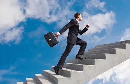 Person in business attire climbing stairs towards the sky.