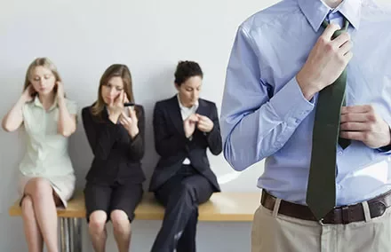 Person adjusting tie with others seated behind them.