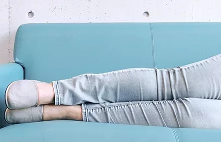 Person lounging with legs stretched out on a blue sofa.