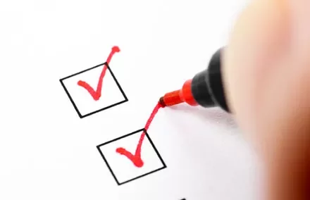 Close-up of a red pen ticking checkboxes on paper.
