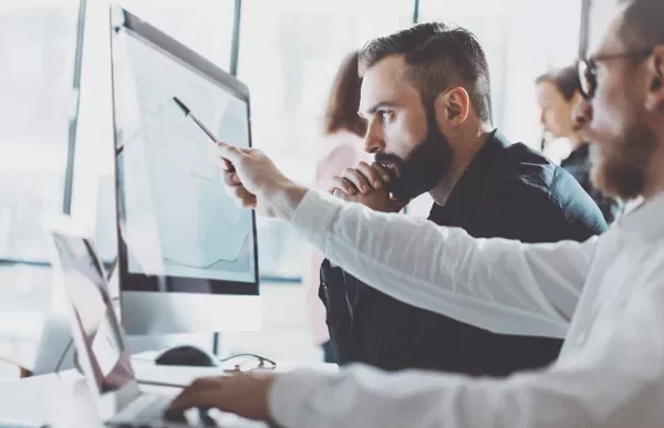 Two people analyzing data on a computer screen.