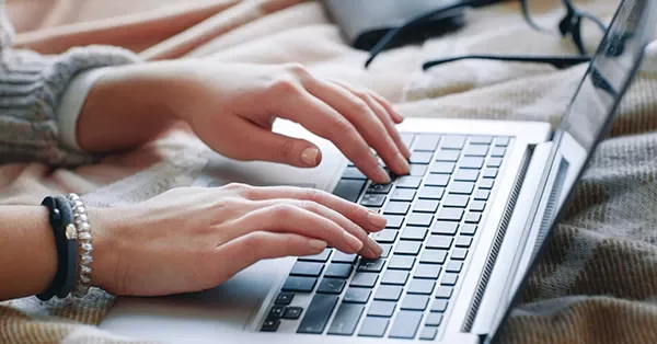 Person typing on a laptop keyboard.