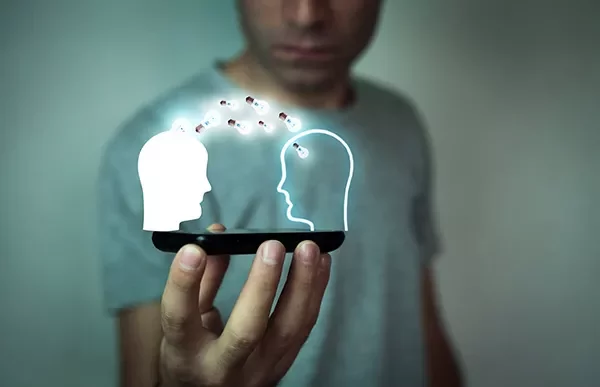 Person holding a hologram of two heads exchanging digital data.